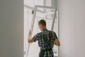 A professional installer fitting a modern window in a well-lit home interior.